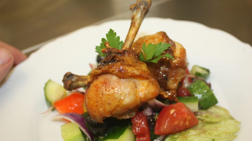 Close-up of a delicious chicken drumstick meal, garnished with fresh veggies.