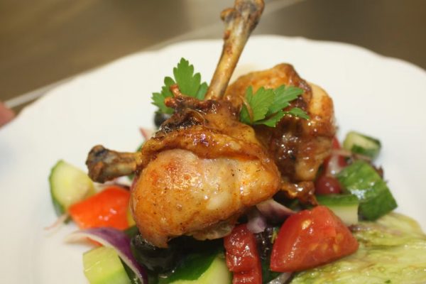 Close-up of a delicious chicken drumstick meal, garnished with fresh veggies.